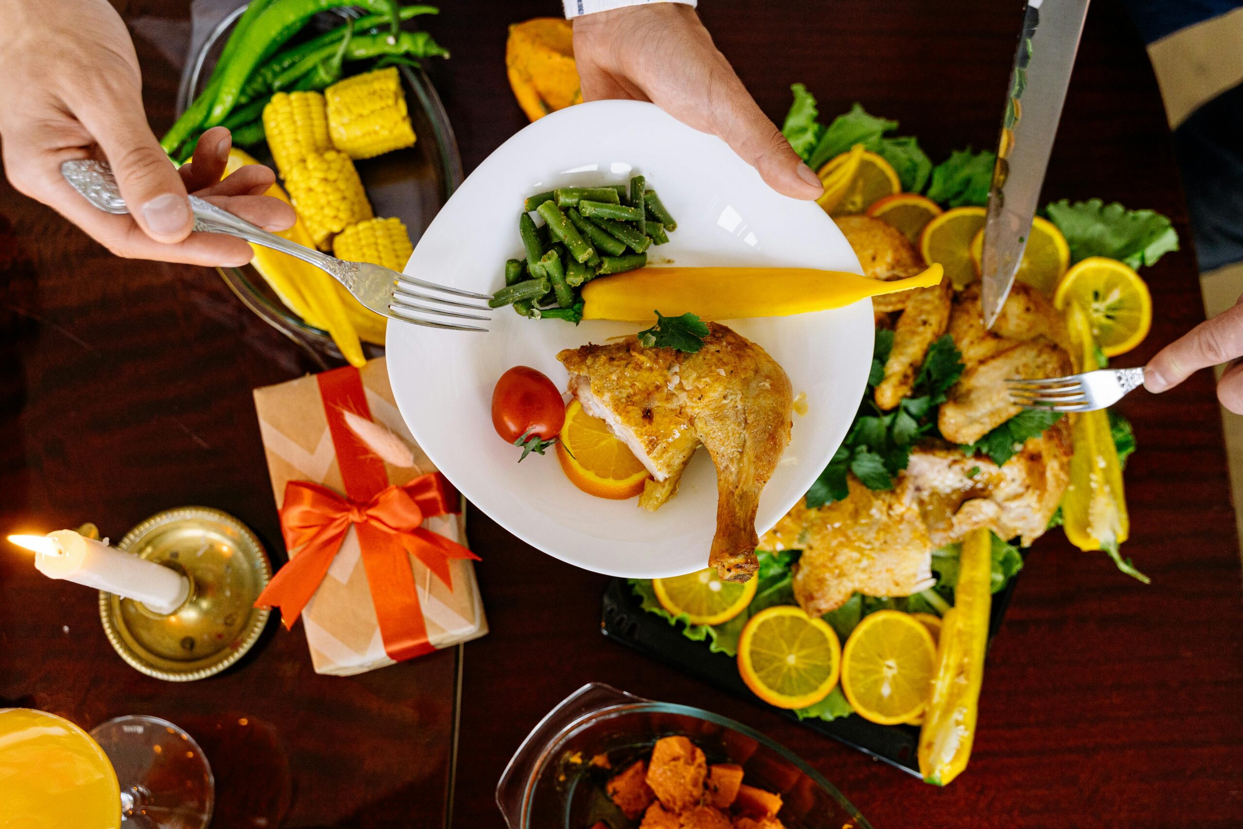 A top view of a roasted chicken dinner with fresh vegetables and citrus garnishes, perfect for festive gatherings.